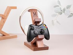 a wooden stand with a game controller on it and a plant in the back ground