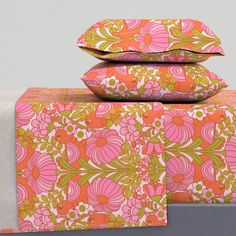 three pillows are stacked on top of each other with pink and green floral designs in the background