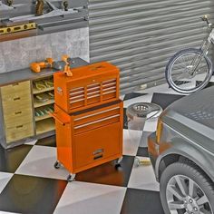 an orange tool box sitting on top of a checkered floor next to a bike