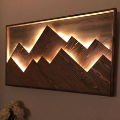 a wooden wall hanging on the side of a white wall with mountains in front of it