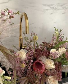 a vase filled with lots of flowers next to a faucet