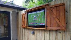 a flat screen tv mounted to the side of a wooden fence