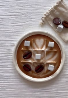 hot chocolate with marshmallows in a bowl on a white tablecloth next to an oven mitt