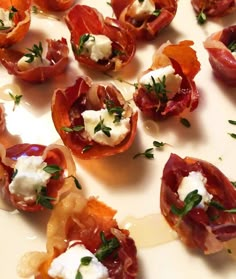 small appetizers are arranged on a plate with cheese and herbs sprinkled on them