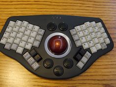 a computer keyboard with an apple on the top and two keys below it, sitting on a wooden table