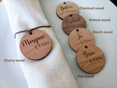 four wooden tags with names on them sitting next to a white napkin and some other items