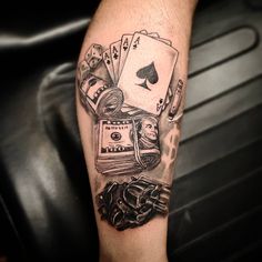 a man's arm with playing cards, money and poker chips tattooed on it