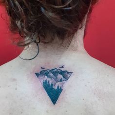 the back of a woman's neck with a mountain tattoo on it