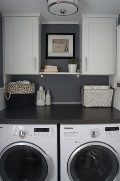 a washer and dryer in a laundry room with white cabinets, gray counter tops