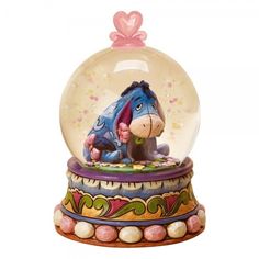 a glass snow globe with a cartoon character inside and a pink bow on the top