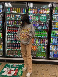 a woman standing in front of a display of sodas and soft drinks at a store