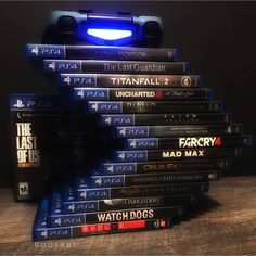 a stack of video games sitting on top of a wooden table next to a blue light