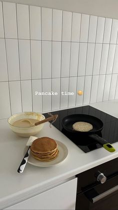 pancake time is cooking on the stove with pancakes in front of it and a skillet next to it