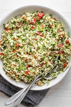 a white bowl filled with coleslaw salad on top of a gray napkin next to a fork