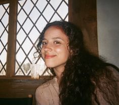 a woman sitting in front of a window smiling