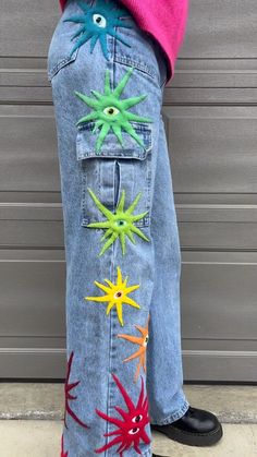 a child's jeans with colorful stars painted on the bottom and sides, standing in front of a garage door