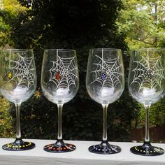 three wine glasses sitting on top of a table next to each other in front of trees