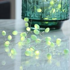 some green balls are sitting on a table next to a vase with flowers in it