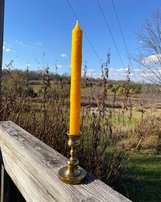 a yellow candle sitting on top of a wooden rail