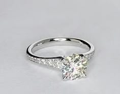 a white gold engagement ring with diamonds on the sides and a single stone in the middle