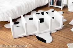 a cow print rug is laying on the floor next to a white bed and bookcase