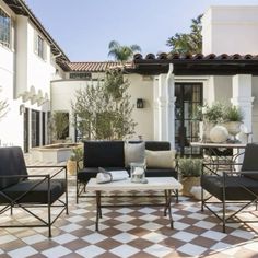 an outdoor living area with black and white checkered tile flooring, furniture and potted plants