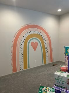 a room with several boxes on the floor and a rainbow painted on the wall behind it