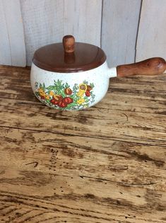 a wooden spoon sitting on top of a table next to a pot with flowers painted on it