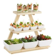 a three tiered food display with salads and appetizers on the top