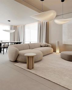 a living room filled with furniture next to a dining table and two large round lamps