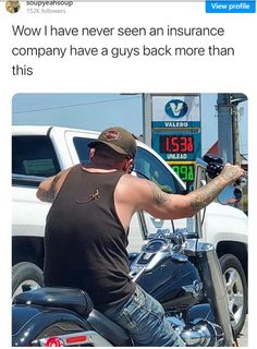 a man riding on the back of a motorcycle next to a gas station with his arm in the air