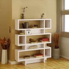 a white shelf with books and vases on it