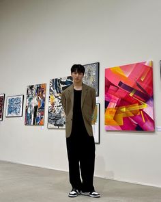 a man standing in front of paintings on the wall