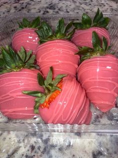 chocolate covered strawberries in a plastic container on a marble counter top with green leaves