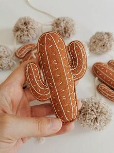 a hand holding a small felt cactus ornament in it's right hand