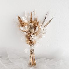 a bunch of dried flowers sitting on top of a white table next to a wall