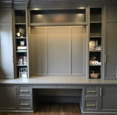 an office desk with built in cabinets and shelves on the wall, along with a hardwood floor