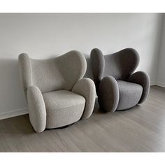 two chairs sitting next to each other on top of a hard wood floor in front of a white wall