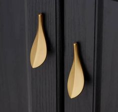 two gold leaf handles on black cabinets