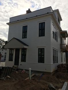 a large white house sitting on top of a dirt field