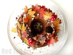 a cake decorated with autumn leaves and nuts on a white plate, ready to be eaten