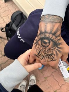 a person holding their hand with an eye tattoo on it's left arm and the word beauty written in cursive writing across the palm