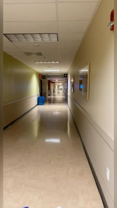 an empty hallway with blue trash cans on the floor