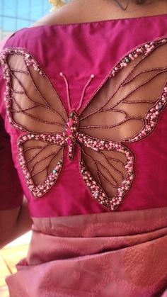 the back of a woman's pink dress with a butterfly appliqued on it