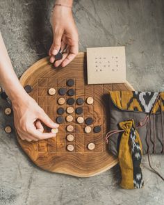 two hands are playing a board game on a table next to other items and cloths