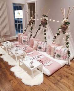 a living room filled with lots of furniture covered in pink and white pillows on top of a hard wood floor