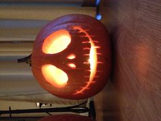 two carved pumpkins sitting on top of a wooden table with their faces glowing in the dark