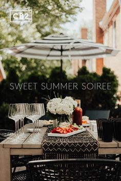 an outdoor dining table with wine glasses and food on it