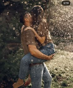 a man holding a woman in his arms as they are splashing water on them