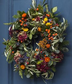 a blue door with a wreath hanging on it's side and flowers in the middle